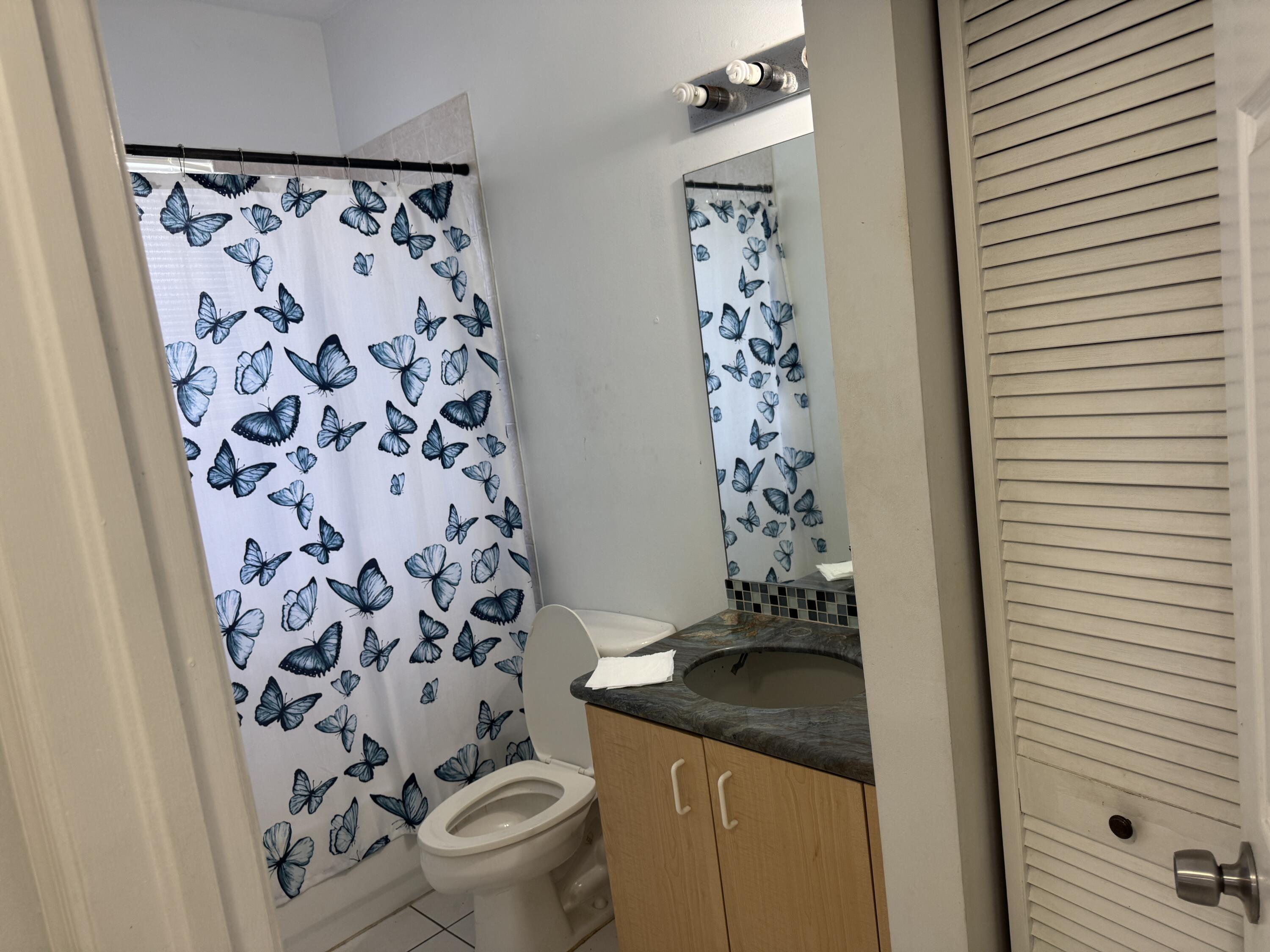 1011 Salmon Isle Greenacres, FL 33413 - Photo 18 of 28 a bathroom with a granite countertop sink a toilet and a shower curtain