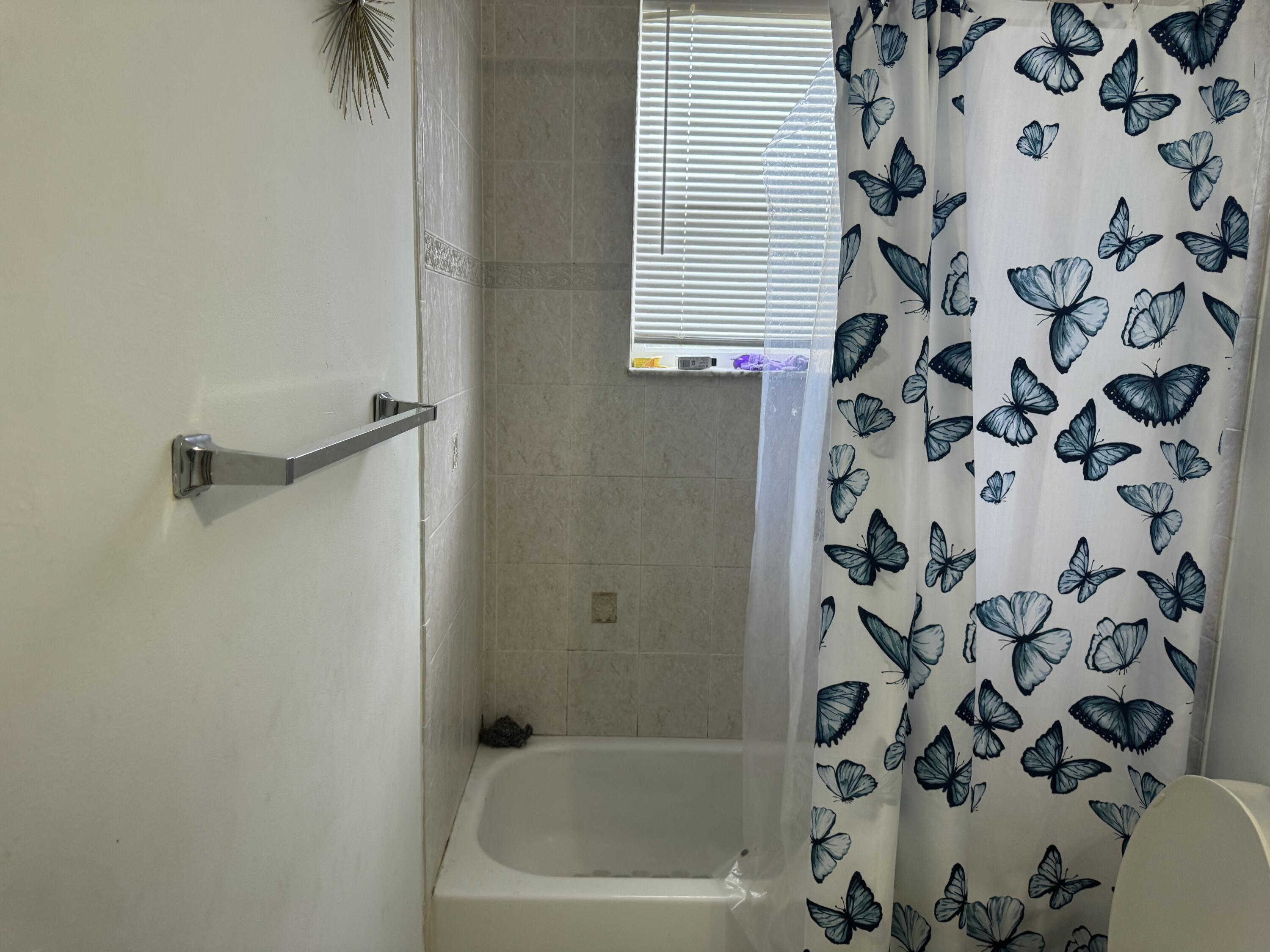 1011 Salmon Isle Greenacres, FL 33413 - Photo 19 of 28 a bathroom with a bathtub and shower curtain