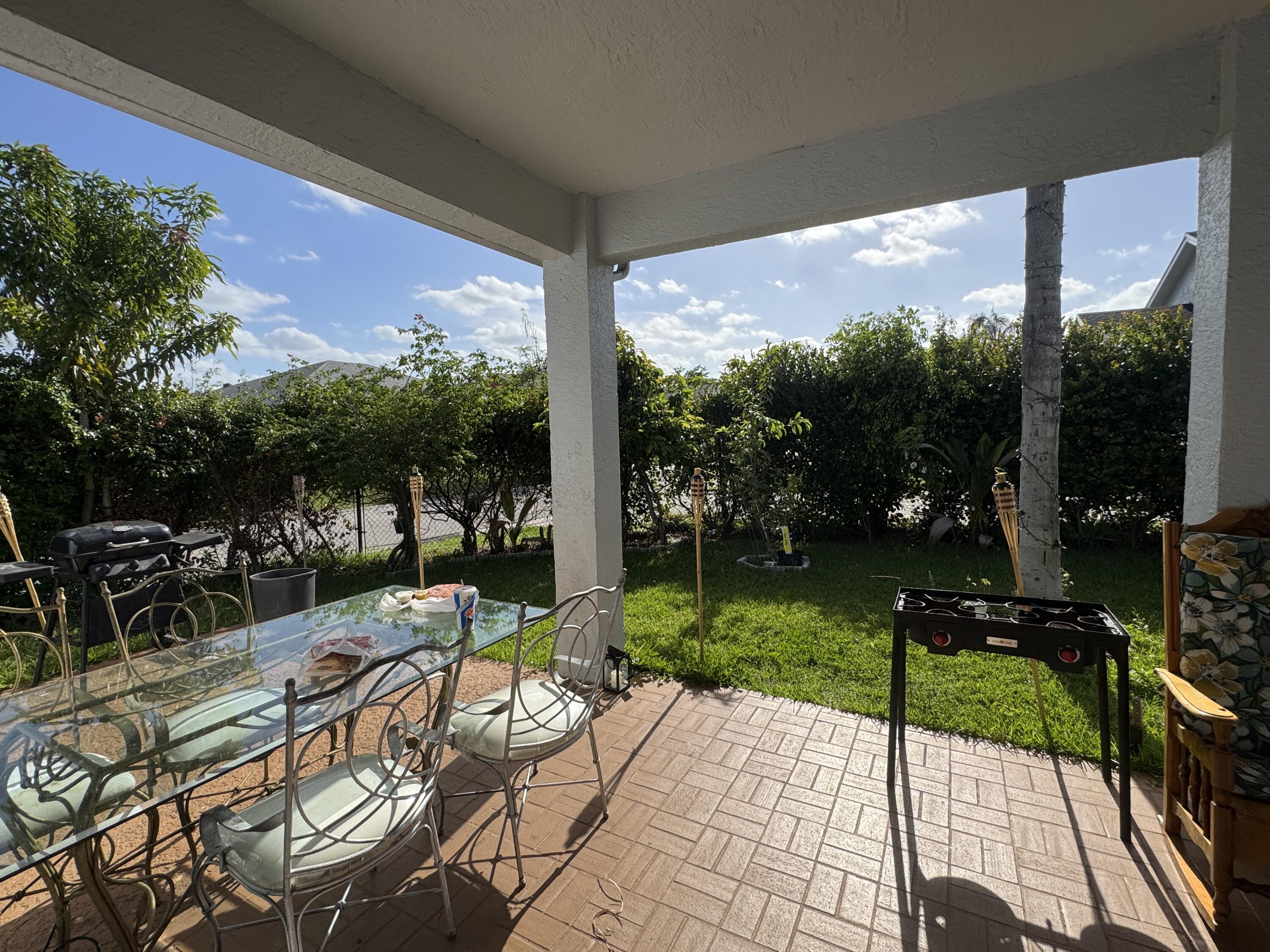 1011 Salmon Isle Greenacres, FL 33413 - Photo 26 of 28 a view of a patio with a table chairs and a floor to ceiling window