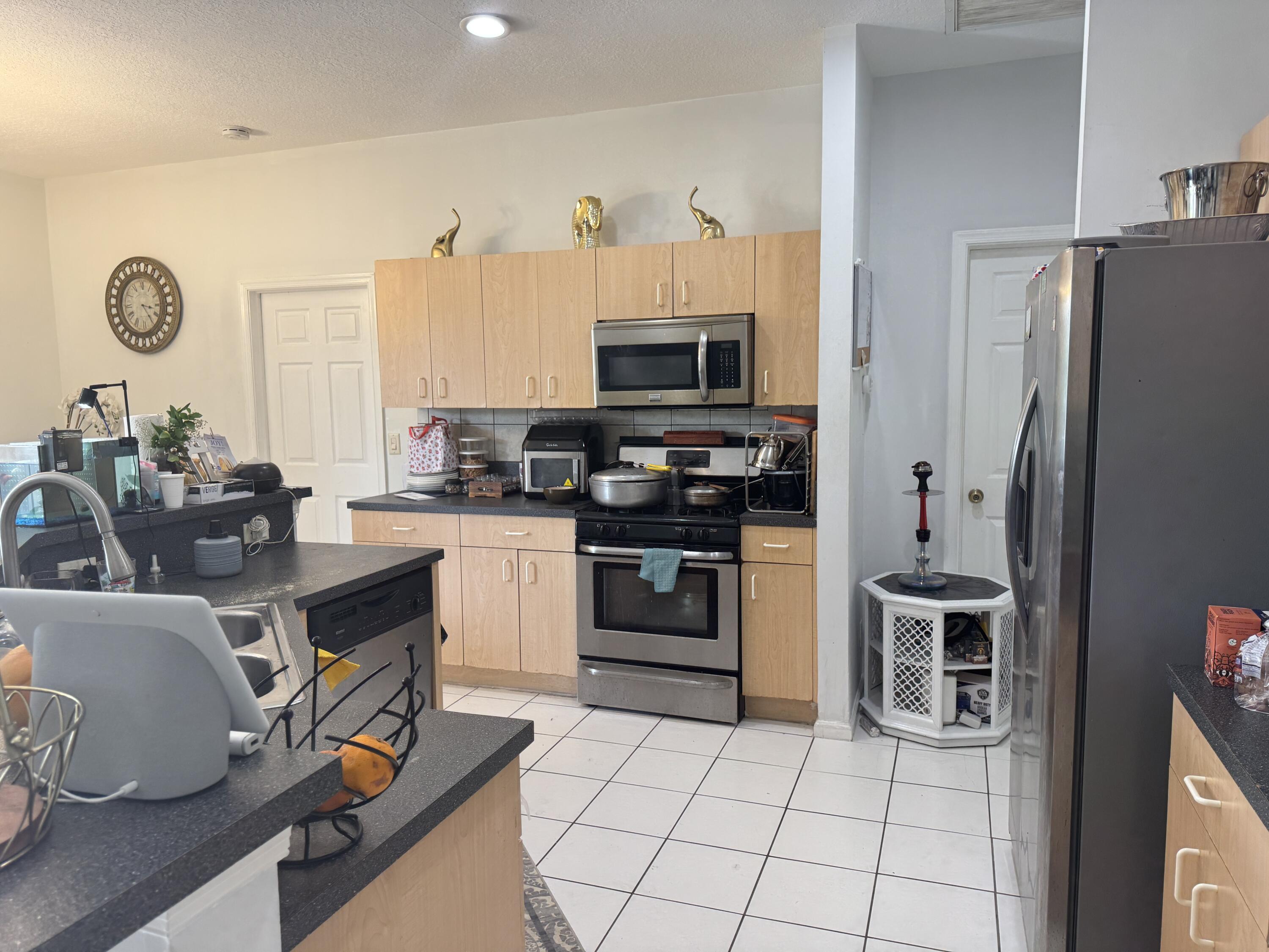1011 Salmon Isle Greenacres, FL 33413 - Photo 9 of 28 a kitchen with a refrigerator a stove a sink and a microwave