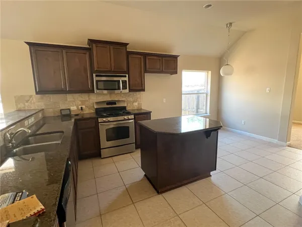 a kitchen with stainless steel appliances granite countertop a stove a sink and a microwave