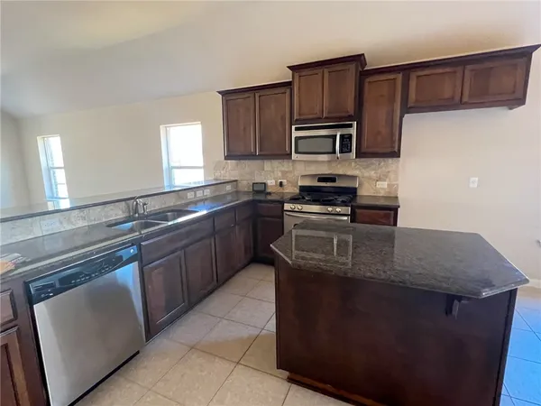 a kitchen with stainless steel appliances granite countertop a stove a sink dishwasher and a refrigerator