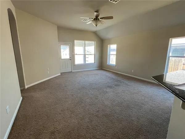 an empty room with windows and ceiling fan