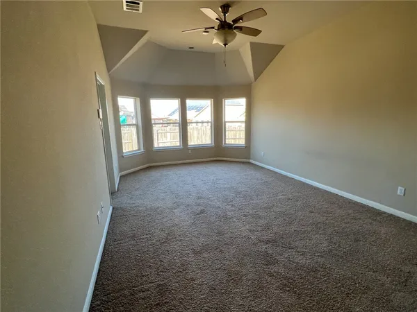 an empty room with windows and fan