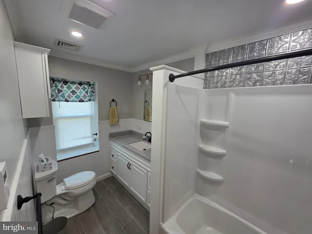 a bathroom with a granite countertop sink toilet a mirror and shower