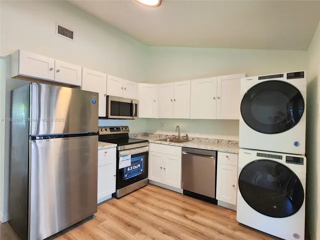 a kitchen with a refrigerator sink and cabinets