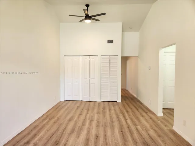 an empty room with wooden floor fan and windows