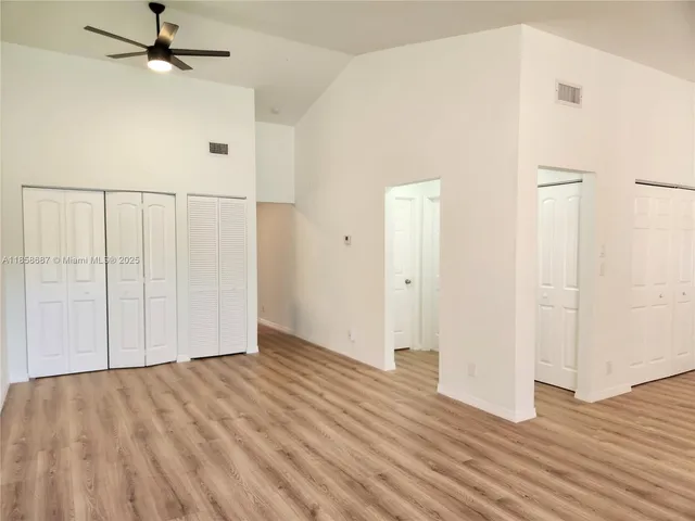 an empty room with wooden floor fan and windows