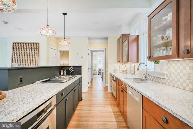 a kitchen with stainless steel appliances granite countertop a stove a sink dishwasher and a refrigerator with wooden floor