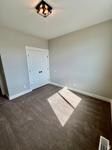 1184 West 3250 North Ogden, UT 84414 - Photo 41 of 69 Neutral-toned room featuring a dark brown patterned carpet, white baseboards, and a white bi-fold closet door