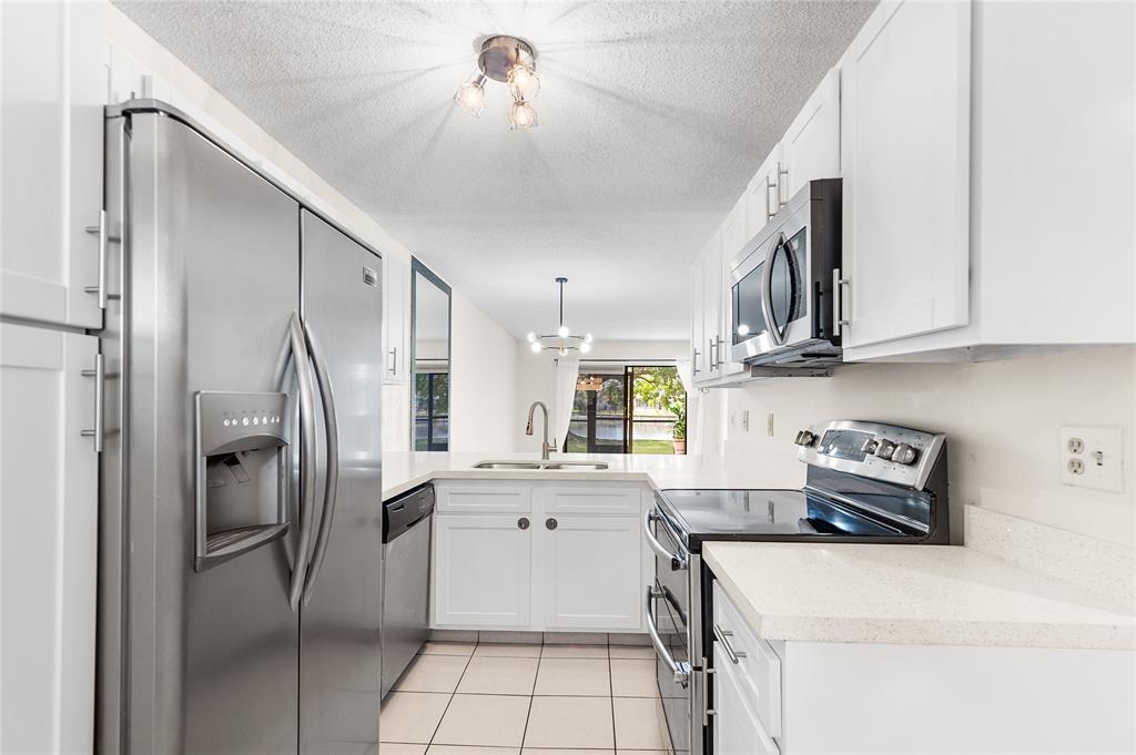 9676 West McNab Road, Unit 110 Fort Lauderdale, FL 33321 - Photo 3 of 26 a kitchen with stainless steel appliances a refrigerator sink and cabinets