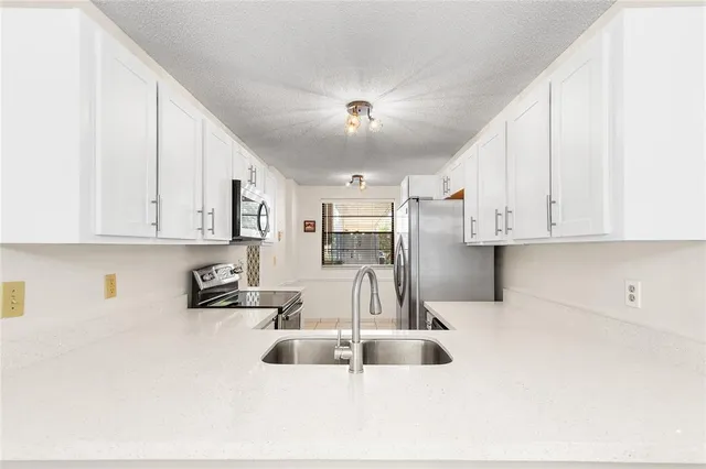 a kitchen with stainless steel appliances a sink a stove and white cabinets