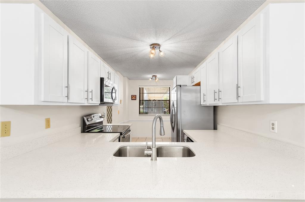 9676 West McNab Road, Unit 110 Fort Lauderdale, FL 33321 - Photo 4 of 26 a kitchen with stainless steel appliances a sink a stove and white cabinets