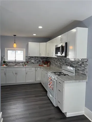 a kitchen with stainless steel appliances granite countertop a stove a sink and a microwave