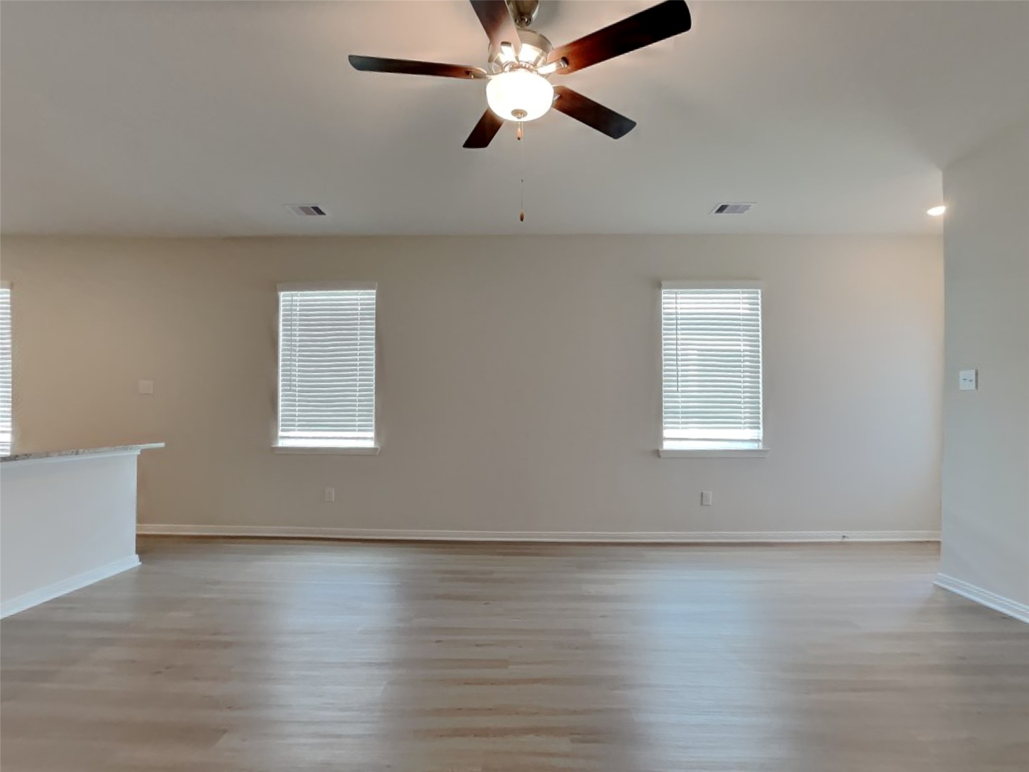 15419 Maple Ter Drive Conroe, TX 77303 - Photo 3 of 26 an empty room with wooden floor chandelier fan and windows