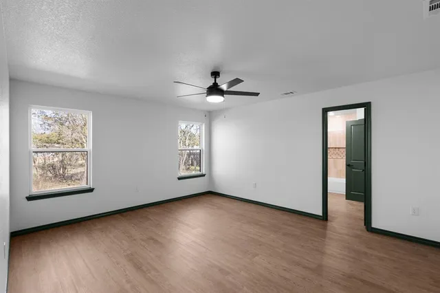 a view of an empty room with a window and wooden floor