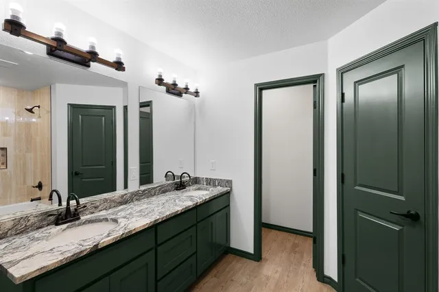 a bathroom with a granite countertop double vanity sink and a mirror