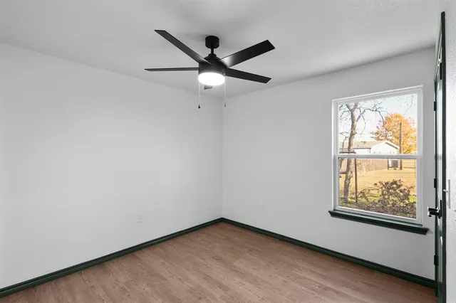 an empty room with windows and fan
