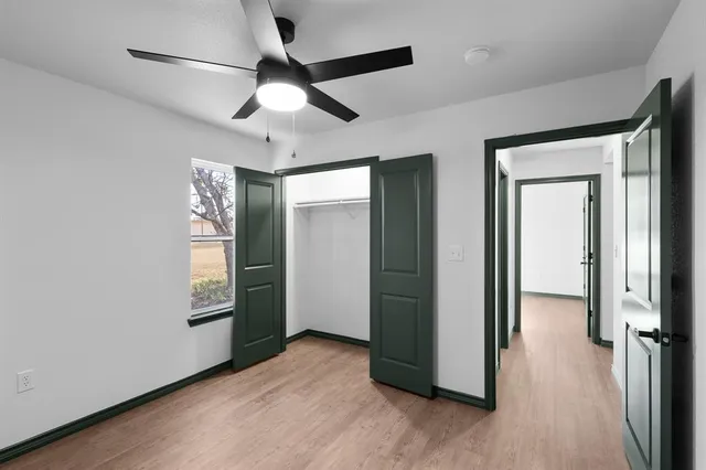 an empty room with wooden floor closet and windows