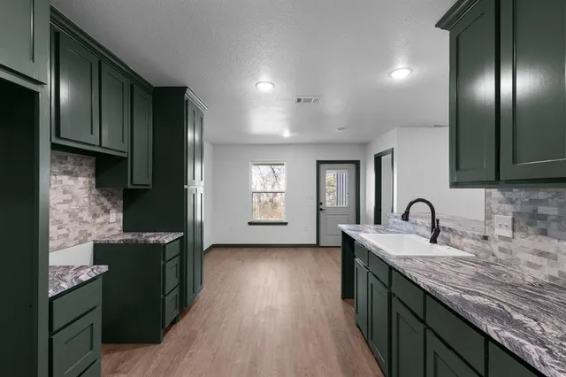 a kitchen with granite countertop a sink stove and cabinets