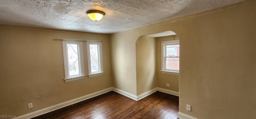 3599 Grosvenor Road Cleveland, OH 44118 - Photo 11 of 25 Spare room with dark wood-style flooring, arched walkways, and a textured ceiling