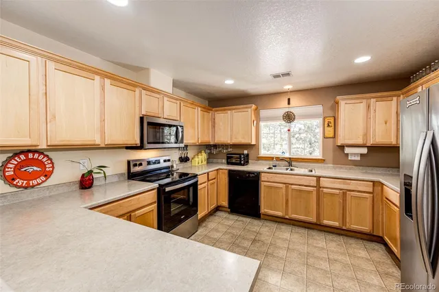 a kitchen with stainless steel appliances granite countertop a stove top oven a sink a dining table and chairs