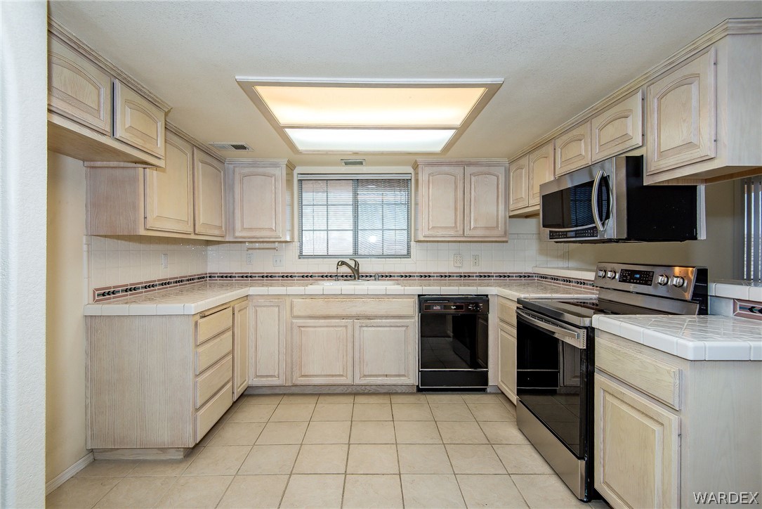 3395 Pegasus Ranch Lane Bullhead City, AZ 86429 - Photo 21 of 50 a kitchen with stainless steel appliances granite countertop a sink and dishwasher a stove top oven with wooden floor