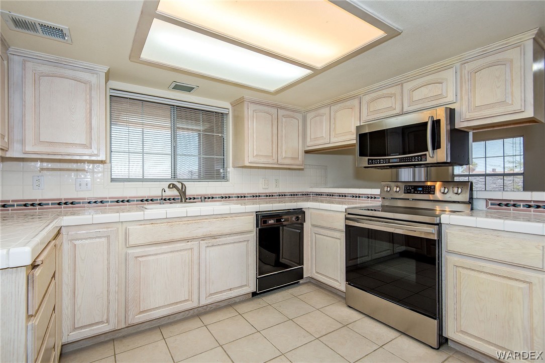 3395 Pegasus Ranch Lane Bullhead City, AZ 86429 - Photo 22 of 50 a kitchen with white cabinets stainless steel appliances and sink
