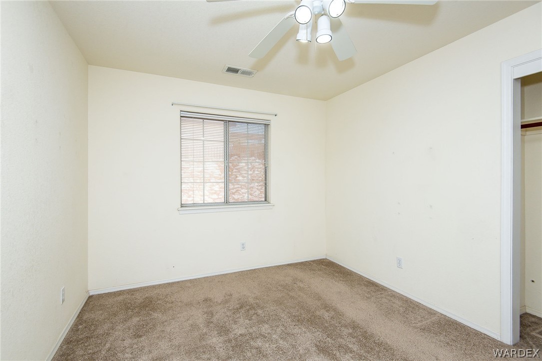 3395 Pegasus Ranch Lane Bullhead City, AZ 86429 - Photo 40 of 50 an empty room with a chandelier fan and windows