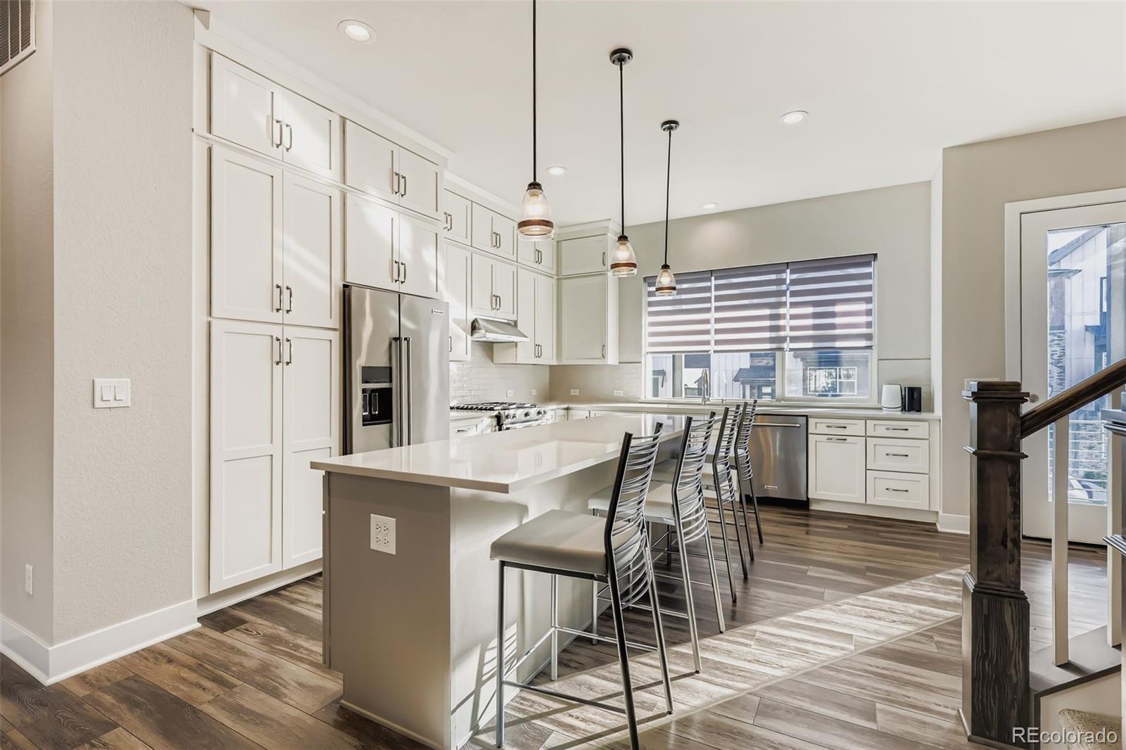 12355 West 51st Avenue Wheat Ridge, CO 80033 - Photo 5 of 17 a kitchen with stainless steel appliances kitchen island granite countertop a table chairs and a wooden floor