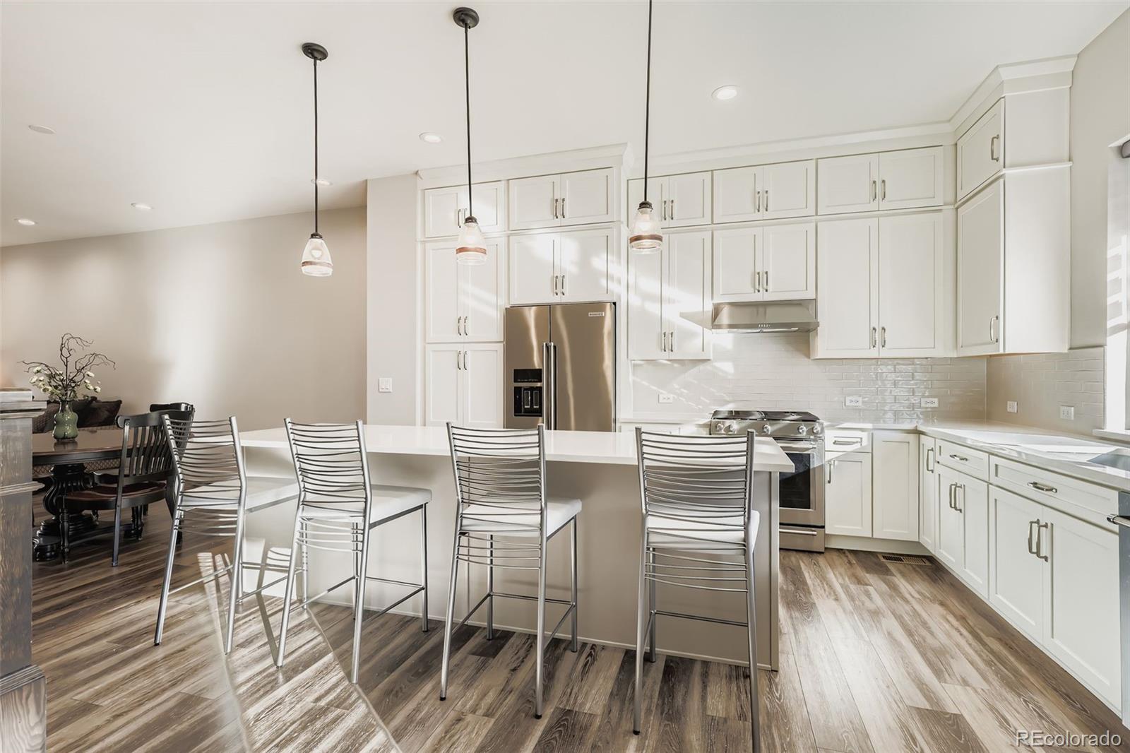 12355 West 51st Avenue Wheat Ridge, CO 80033 - Photo 6 of 17 a kitchen with stainless steel appliances granite countertop a stove a refrigerator a kitchen island a table and chairs with wooden floor