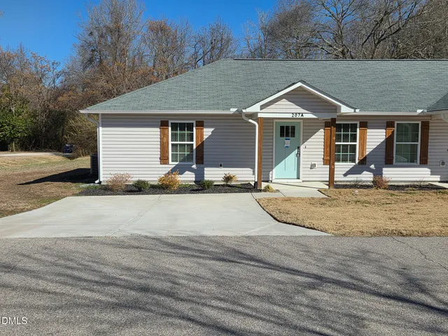 a view of a house with a yard and large tree
