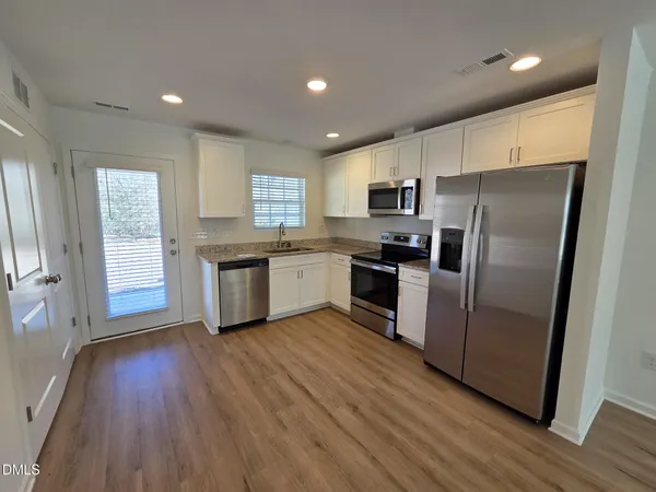 a kitchen with wooden floors and stainless steel appliances