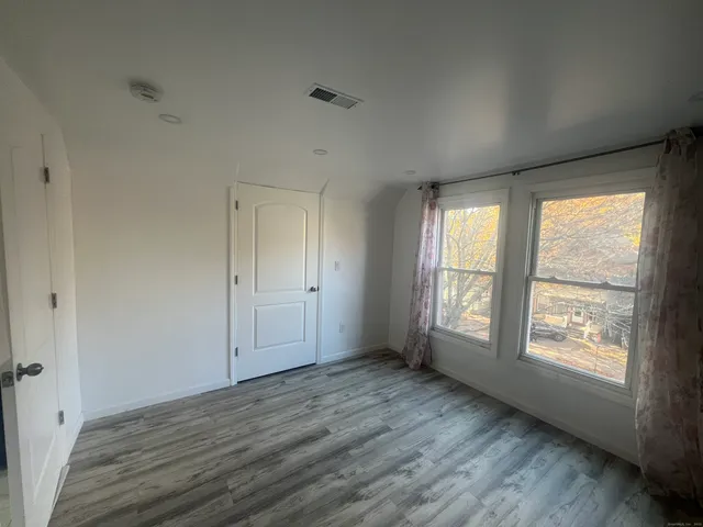 an empty room with wooden floor and windows