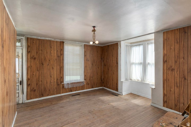 482 West 100 N Street Beaver, UT 84713 - Photo 19 of 41 Empty room with wood walls, wood finished floors, and a chandelier