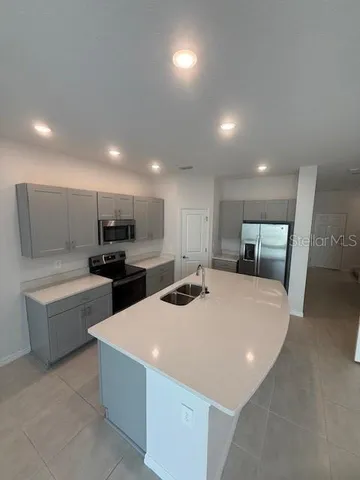 a kitchen with sink a refrigerator and chairs