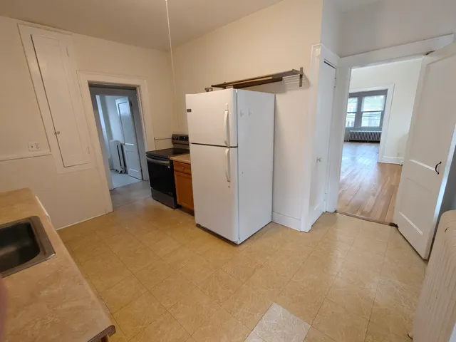 a view of a kitchen with refrigerator and wooden floor