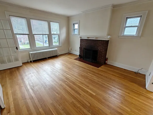 a view of an empty room with wooden floor and a window