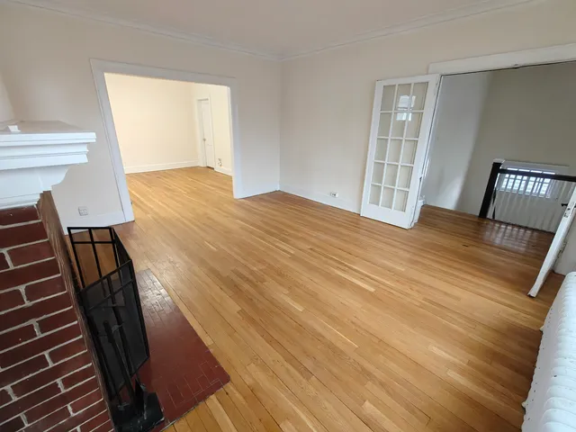a view of an empty room with wooden floor and stairs