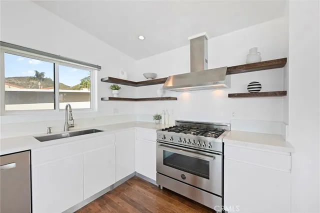 a kitchen with cabinets wooden floor appliances and a sink