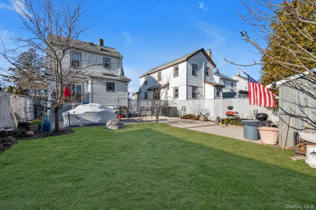 a white house that has a small yard and couches chairs with wooden fence