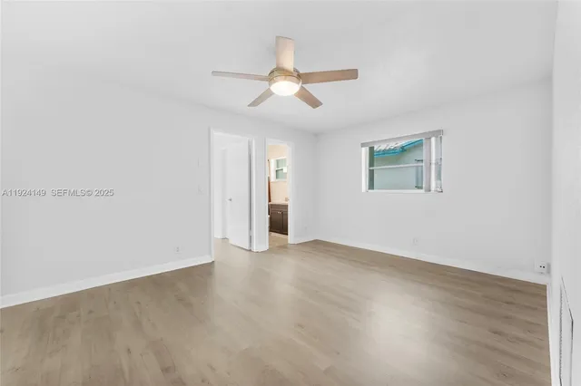 an empty room with wooden floor ceiling fan and windows