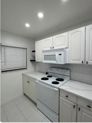 a kitchen with granite countertop a sink a stove and cabinets
