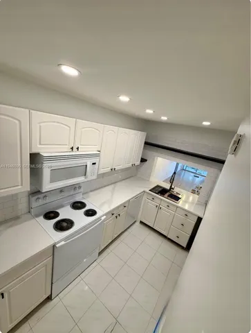 a kitchen with stainless steel appliances granite countertop a stove and white cabinets