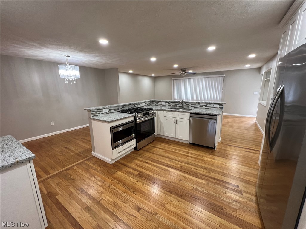 5105 Hillside Road Independence, OH 44131 - Photo 13 of 35 Kitchen featuring sink, light hardwood / wood-style flooring, ceiling fan with notable chandelier, pendant lighting, and white cabinetry