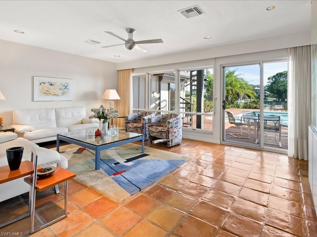 154 Cajeput Drive Naples, FL 34108 - Photo 23 of 45 a living room with furniture a flat screen tv and a floor to ceiling window