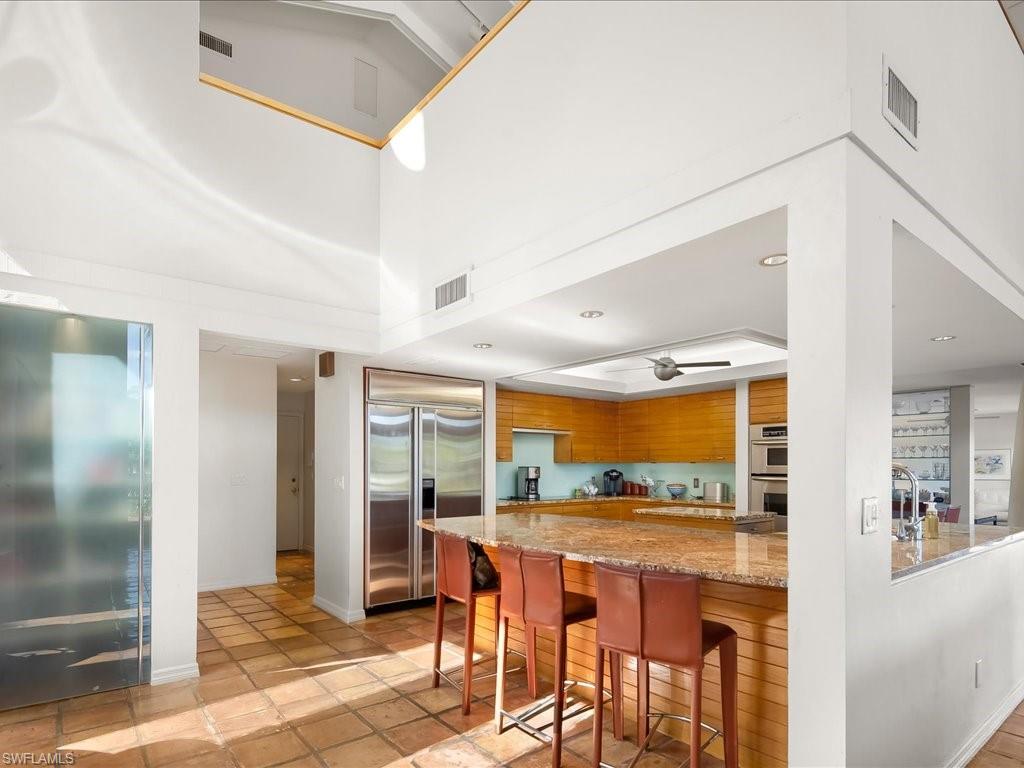 154 Cajeput Drive Naples, FL 34108 - Photo 30 of 45 a dining room with stainless steel appliances kitchen island granite countertop a refrigerator and a sink