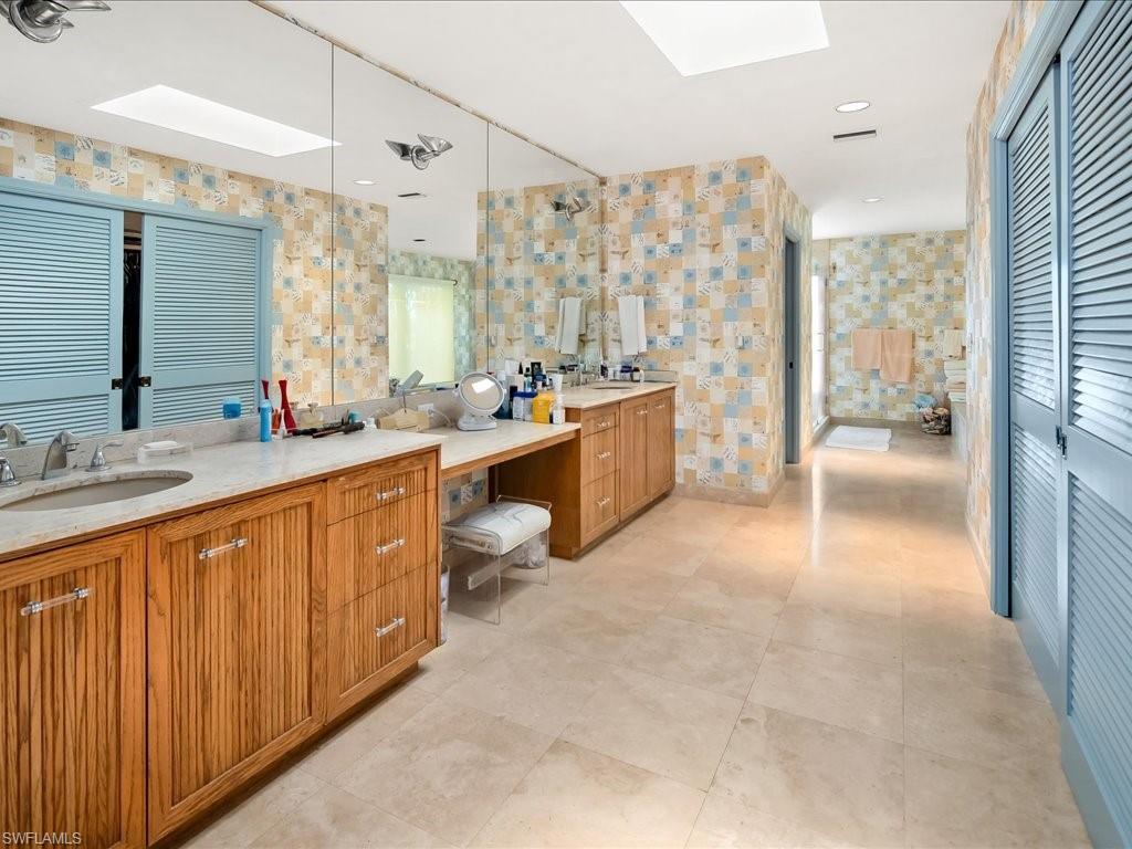 154 Cajeput Drive Naples, FL 34108 - Photo 37 of 45 a large bathroom with a double vanity sink a large mirror and a bathtub