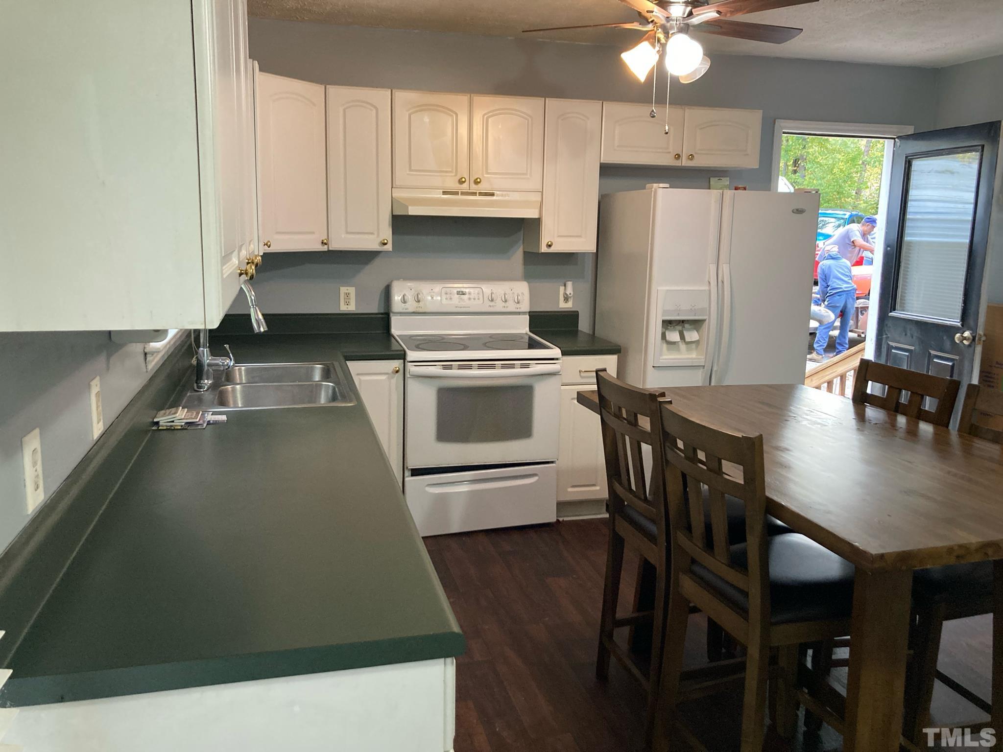 5924 Virgilina Road Roxboro, NC 27574 - Photo 4 of 6 a kitchen with a sink a stove a refrigerator and white cabinets
