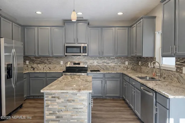 a kitchen with kitchen island granite countertop a stove sink cabinets and refrigerator